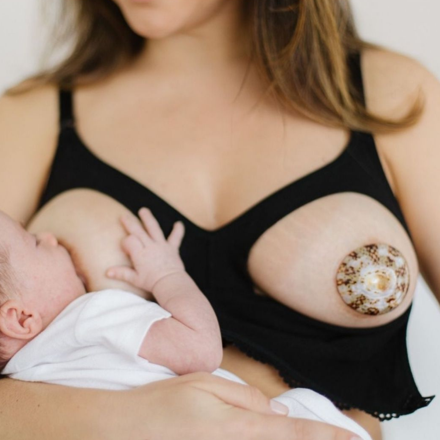Maman allaitant son bébé avec coquillages d'allaitement en nacre pour protéger les mamelons