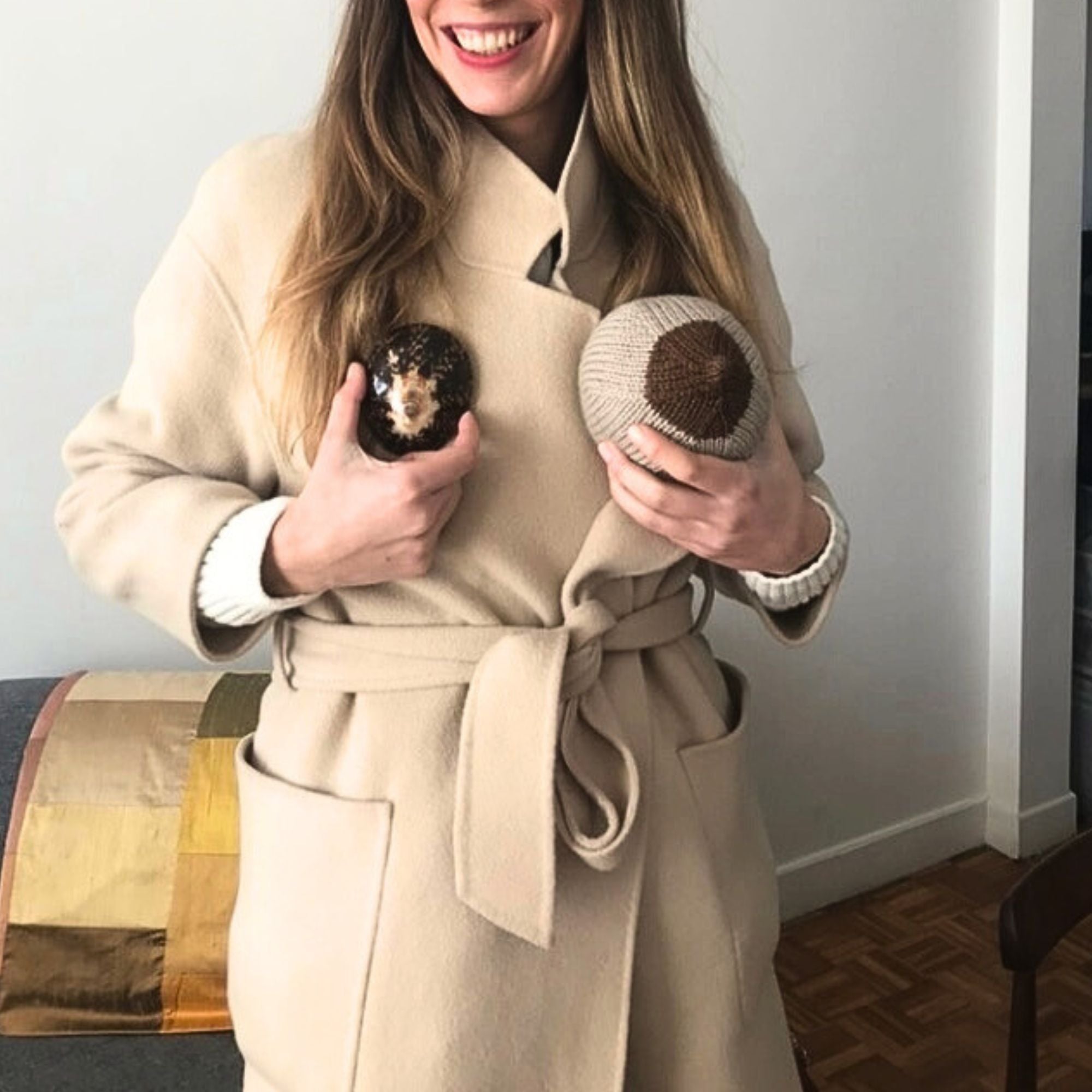 Femme souriante présentant avec humour nos coquillages d’allaitement à l’aide de coussins en forme de seins. Un clin d’œil à notre engagement : offrir aux mamans des coquillages bien adaptés à leur morphologie, dans une relation directe et bienveillante avec chacune d’elles.