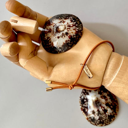 Ensemble BEBE NACRE Maison Nacre : coquillages d’allaitement en nacre naturelle avec bracelet d’allaitement, bijou maternel pour le rythme des tétées, presenté sur une main en bois 